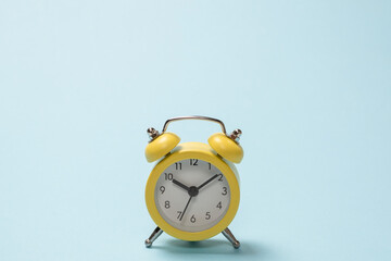 Yellow alarm clock on a blue background. Copy space.