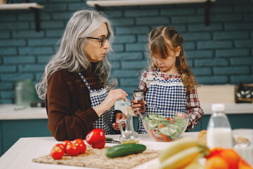 Cute girl and her grandparents cooking in kitchen