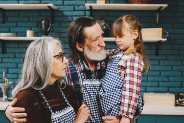 Senior grandparents couple with dgranddaughter cooking in kitchen
