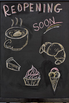 Part of blackboard with drawn pastry items and drink and reopening announcement