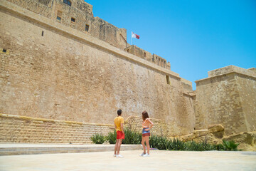 A couple standing near the wall of Castello citadel of Victoria in Gozo, Malta