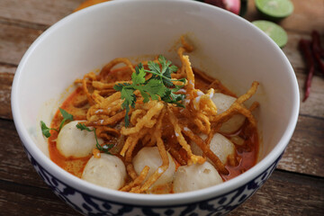 Local northern Thai food Egg noodle curry with meatballs on wood background