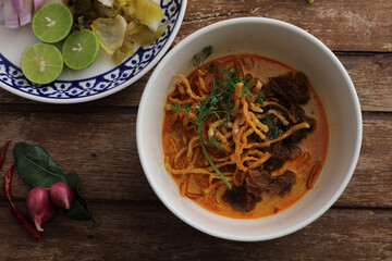 Local northern Thai food Egg noodle curry with beef on wood background