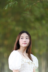 Beautiful young woman with white dress on bamboo forest background