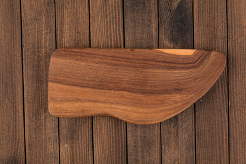Top view on unusual shape wooden cutting board on a wooden background