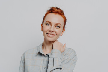 Fototapeta premium Young attractive smiling female with ginger hair in casual outfit isolated on grey studio background
