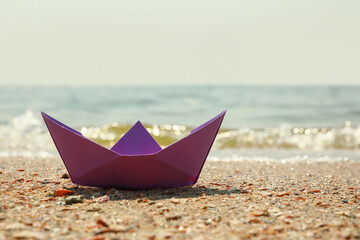Purple paper boat near river on sunny day, space for text