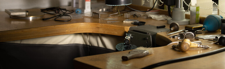 Fototapeta na wymiar Jeweler's workplace. Panorama wide shot. Side view of jeweler's workbenche with different tools on a wooden table. Goldsmith concept background