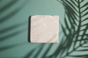 Travertine stone display flat lay podium ongreen background and palm shadow. Product promotion...