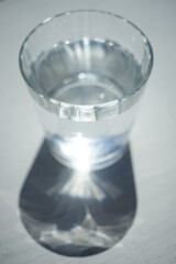 Full glass of water on white sunny table