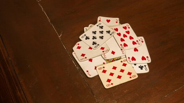  stop morion or time lapse of a deck of playing cards such as poker or rummy, randomly scattered on a dark brown wooden game table