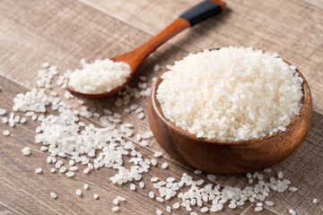 Fototapeta na wymiar Raw white rice in a wooden bowl over table.