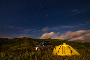 Camping in a meadow under night sky.