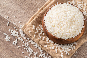 Raw white rice in a wooden bowl over table.