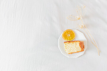 Home office desk frame with laptop, orange piece of cake, headband, glasses, beige wildflowers  and notebook on white background. Flat lay, top view. Feminine business concept.