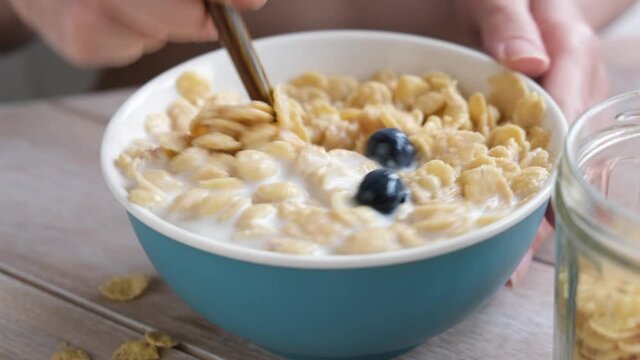 Eating cornflakes with blueberries and almon milk for breakfast. Healthy food