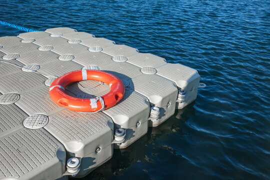 Red life buoy lays on an empty floating pontoon