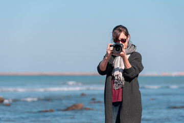 Obraz premium woman photographer taking a photo at the beach 