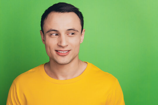 Portrait of charming cheerful guy toothy beaming smile look side blank space on green background