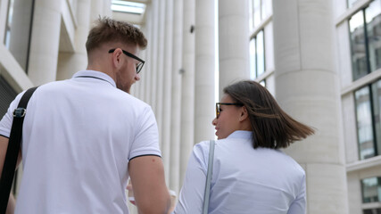 Fototapeta premium Young interracial colleagues with paper coffee cups walking inside modern building