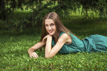 Naklejka na ściany i meble Portrait of a young girl lying on green grass