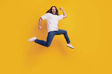 Fototapeta na wymiar Portrait of sporty energetic guy run excited jump on yellow background