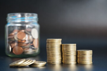 Stack of money coin and coin in a glass jar on black background, Saving money concept