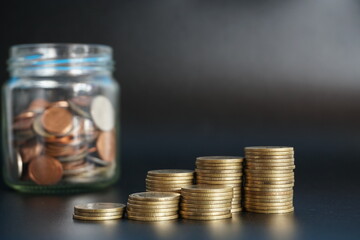Stack of money coin and coin in a glass jar on black background, Saving money concept