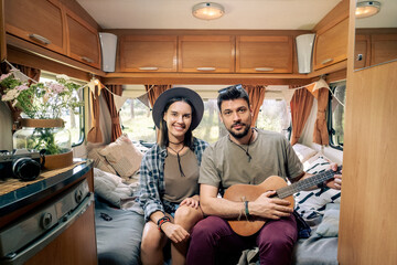 Naklejka premium Young couple of tourists enjoying summer vacation inside house on wheels