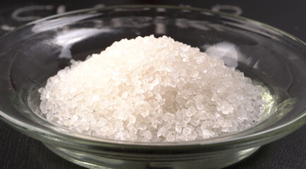 Sugar in glass bowl on wooden background.