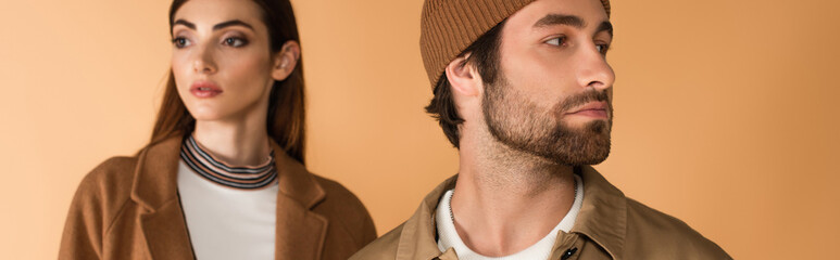 Obraz premium fashionable couple in autumn clothes looking away isolated on beige, banner