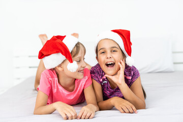 two little girls friends or sisters with hats and playing and cuddling and laughing at winter time