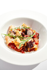 Cannelloni pasta with seafood and Parmesan cheese. Lasagna cannelloni pasta stuffed with tomato sauce and fried octopus. Italian pasta in white plate isolated on white background .