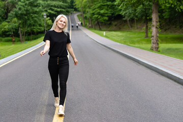 Attractive young woman walks along the line of the road enjoying nature.