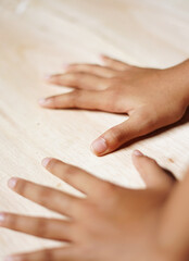 A child's hand is placed on a wooden plank