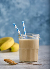 Healthy banana peanut butter smoothie on blue background. Copy space concept.