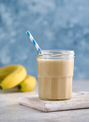 Healthy banana peanut butter smoothie on blue background. Copy space concept.