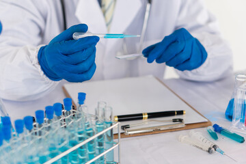Fototapeta premium a professional scientist or researcher holding a test tube The pipette lowers the sample into the test tube. by virus analysis Corona COVID-19 in the near term scientific laboratory test
