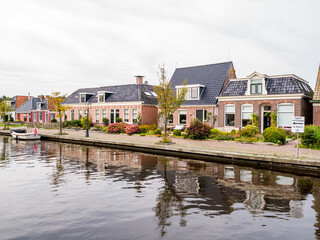 Fototapeta na wymiar Houses by canal in village of Warten, Leeuwarden, Friesland, Netherlands