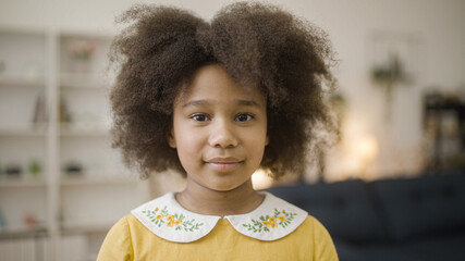 Cute Afro-american girl with natural black hair smiling on camera, happy childhood
