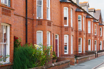 Fototapeta na wymiar Typical red brick Victorian style terraced residential housing with bay windows and small front gardens opening on to a street in the United Kingdom