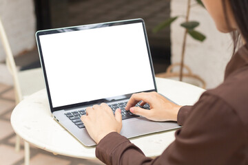 Woman using or typing laptop outside cafe restaurant with natural. Laptop computer on white desk and white blank on screen.