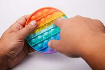 Multi-colored children's toy Pop it in the hands on a white background