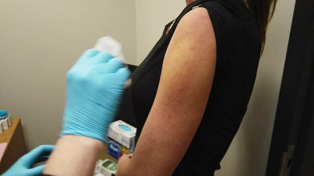 Nurse Administers A Coronavirus COVID-19 Vaccine Shot To An Adult Female Patient
