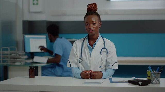 Black medic on video call online conference sitting at desk in medical cabinet. African american doctor using remote communication method on internet for telemedicine treating people