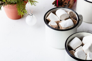 Hot cocoa in white mugs with  sweet marshmallows  on white table