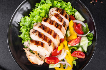 salad grilled chicken breast vegetables tomato, cucumber, onion, pepper outdoor meal snack on the table copy space food background rustic. top view keto or paleo diet