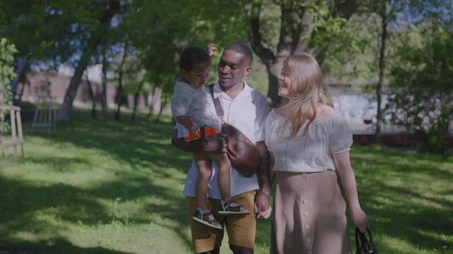 Multiracial family together. Summer sunny day in the city park. Mom dad and son on vacation on a weekend.