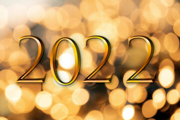 The year 2022 written on wooden cubes in gold luxury letters with shiny bokeh background, New Year celebration concept glitter