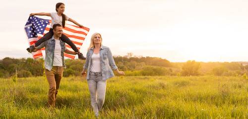 Beautiful family with the American flag in a field at sunset. Independence Day, 4th of July.